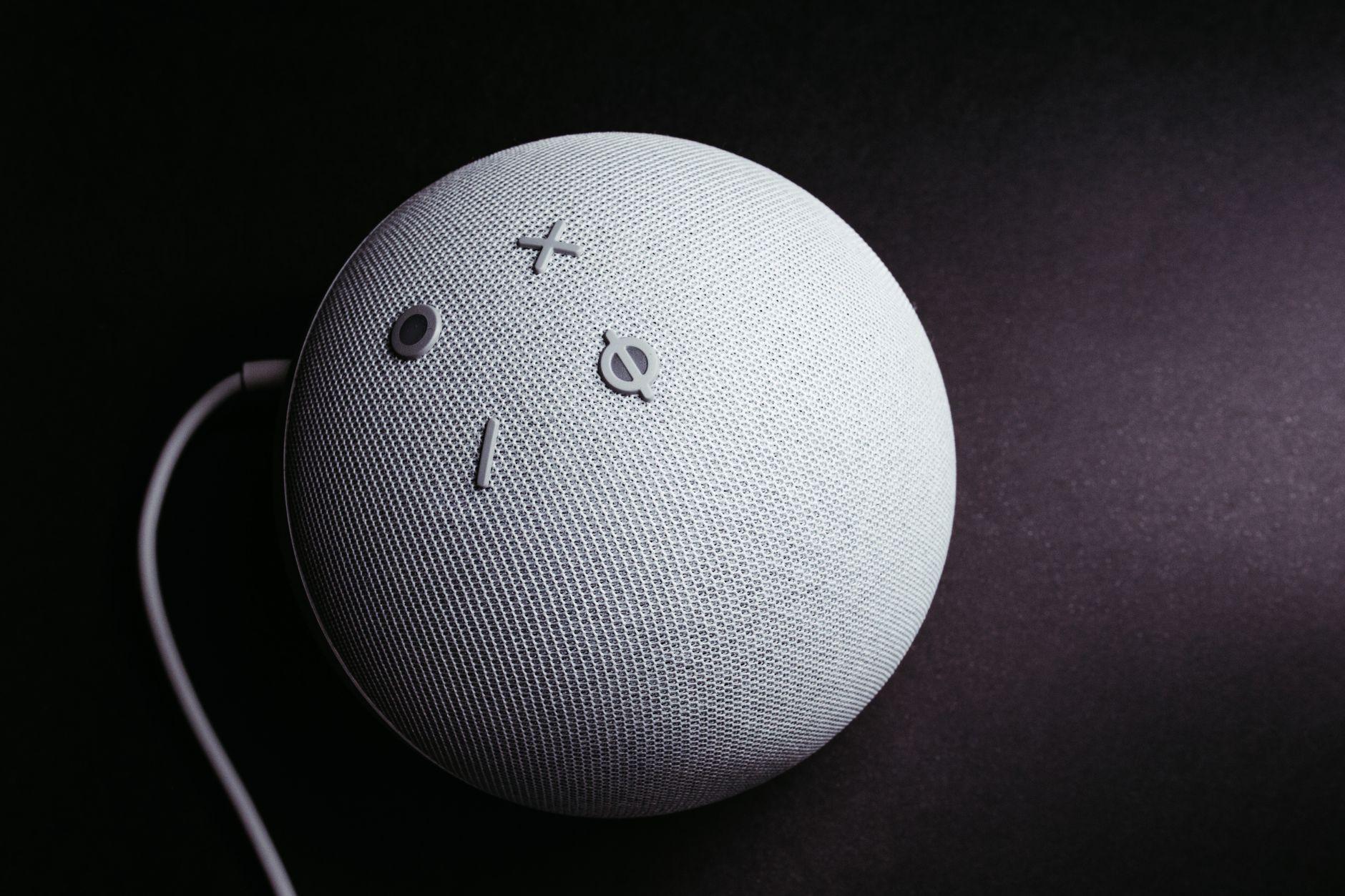 Close-up of a smart speaker on a black background, showcasing minimalistic elegance.