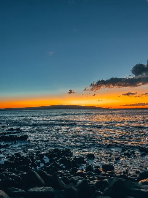 Free Vibrant sunset over ocean with rocky shore, capturing the essence of serene nature. Stock Photo
