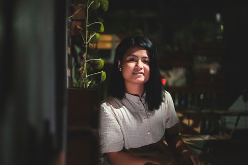Free A young woman smiles warmly while sitting outdoors in Dhaka, Bangladesh at night. Stock Photo