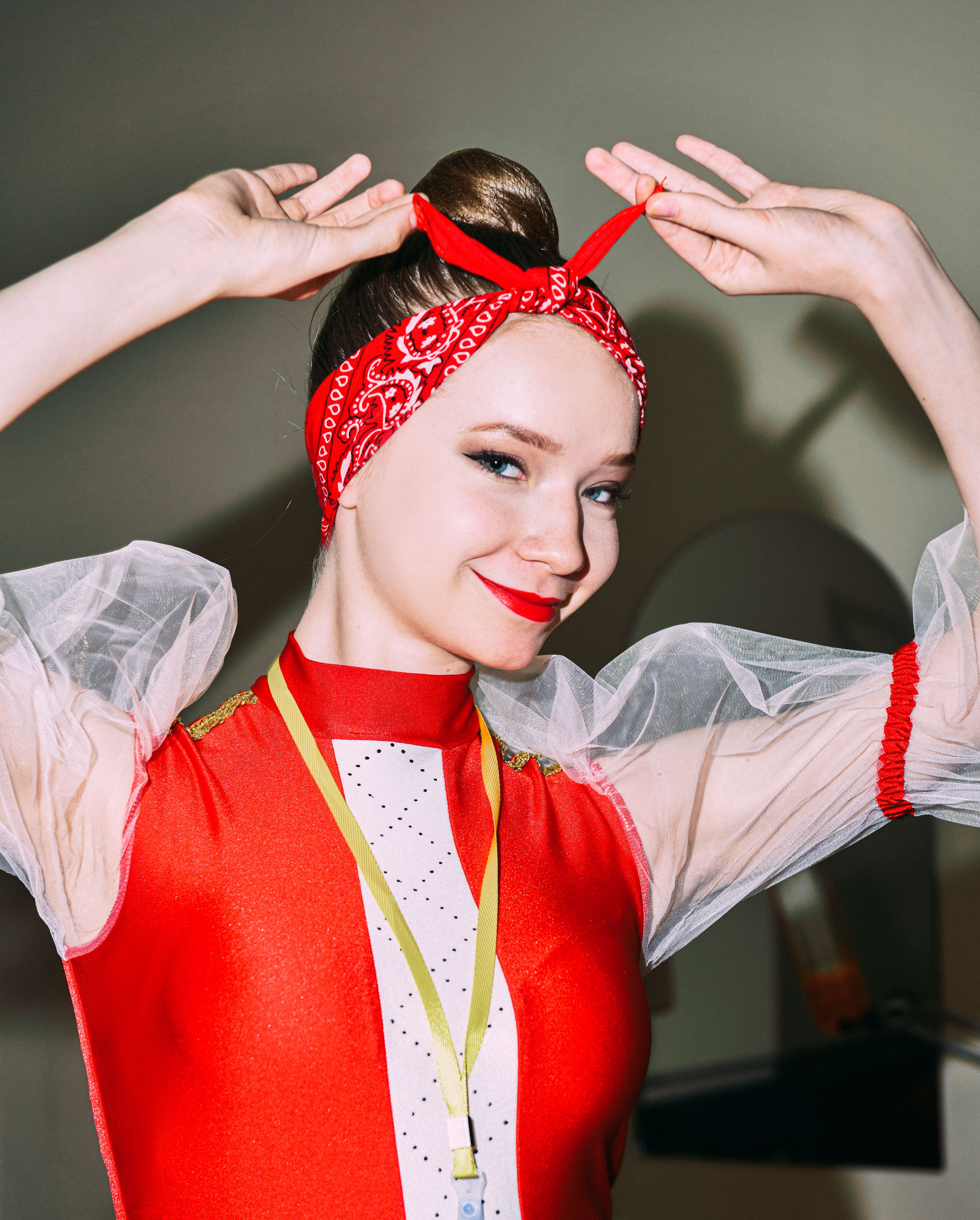 Smiling woman dressed in vibrant retro attire with a red bandana and stylish outfit.