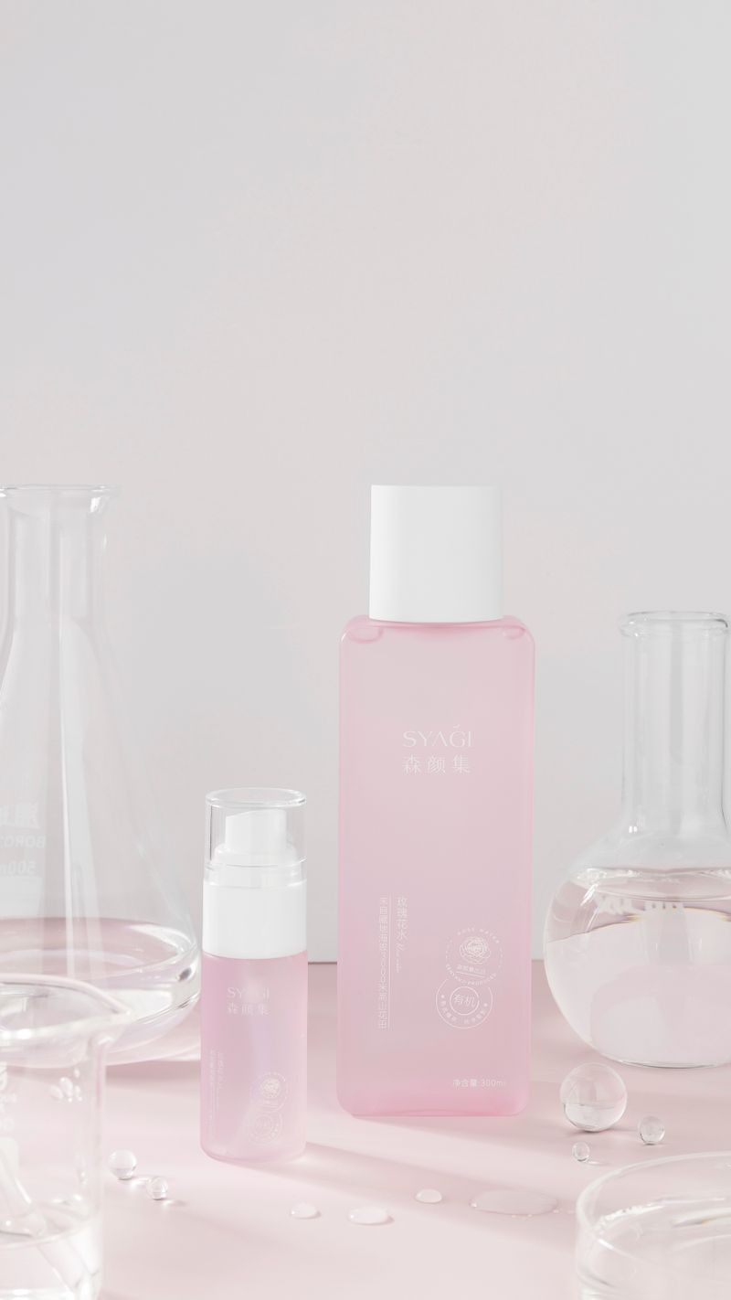 Pink skincare essence bottles with laboratory glassware on a minimal background