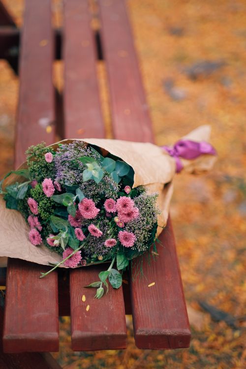 Free Elegant bouquet with pink flowers resting on a wooden bench over autumn leaves. Stock Photo