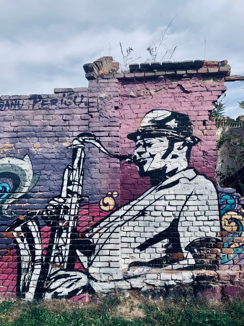 Free Vibrant street art of a saxophonist on a weathered brick wall in Niš, Serbia. Stock Photo