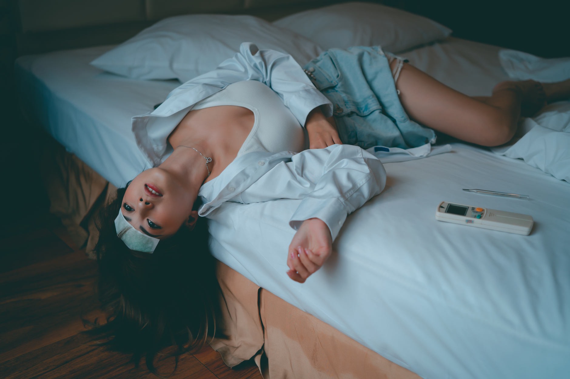 A woman lying on a bed with a cooling patch, feeling unwell and resting.
