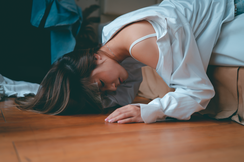 Free Woman lying gracefully on floor, wearing casual white shirt in a relaxed pose. Stock Photo