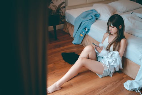 Woman Sitting on the Floor While Using a Cellphone