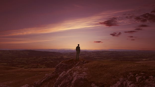 Man standing on a hilltop at twilight in Brecon, Wales, capturing a serene landscape view.