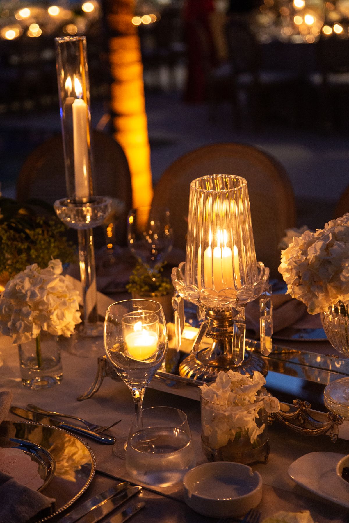 Candles glowing on a set dinner table