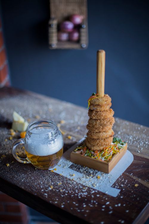 Free A stack of crispy onion rings and a frothy beer served on a wooden table indoors. Stock Photo