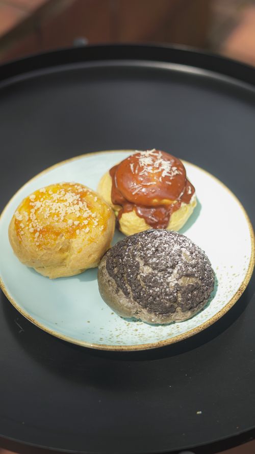 Free Close-up of three gourmet buns with varied toppings on a plate, perfect for bakery promotions. Stock Photo