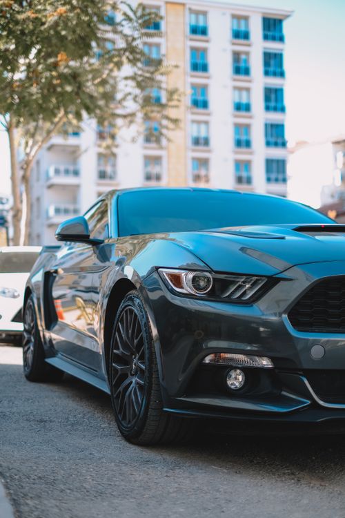 Free Black Ford Mustang sports car parked on an urban street, showcasing its sleek design. Stock Photo