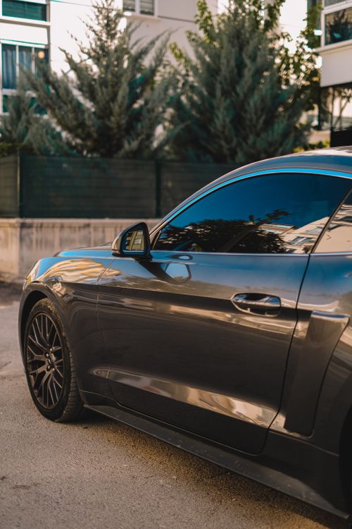 Free Close-up of a black sports car with tinted windows parked outdoors. Stock Photo