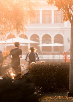 A couple jogging in a sunlit park, enjoying a refreshing morning run.
