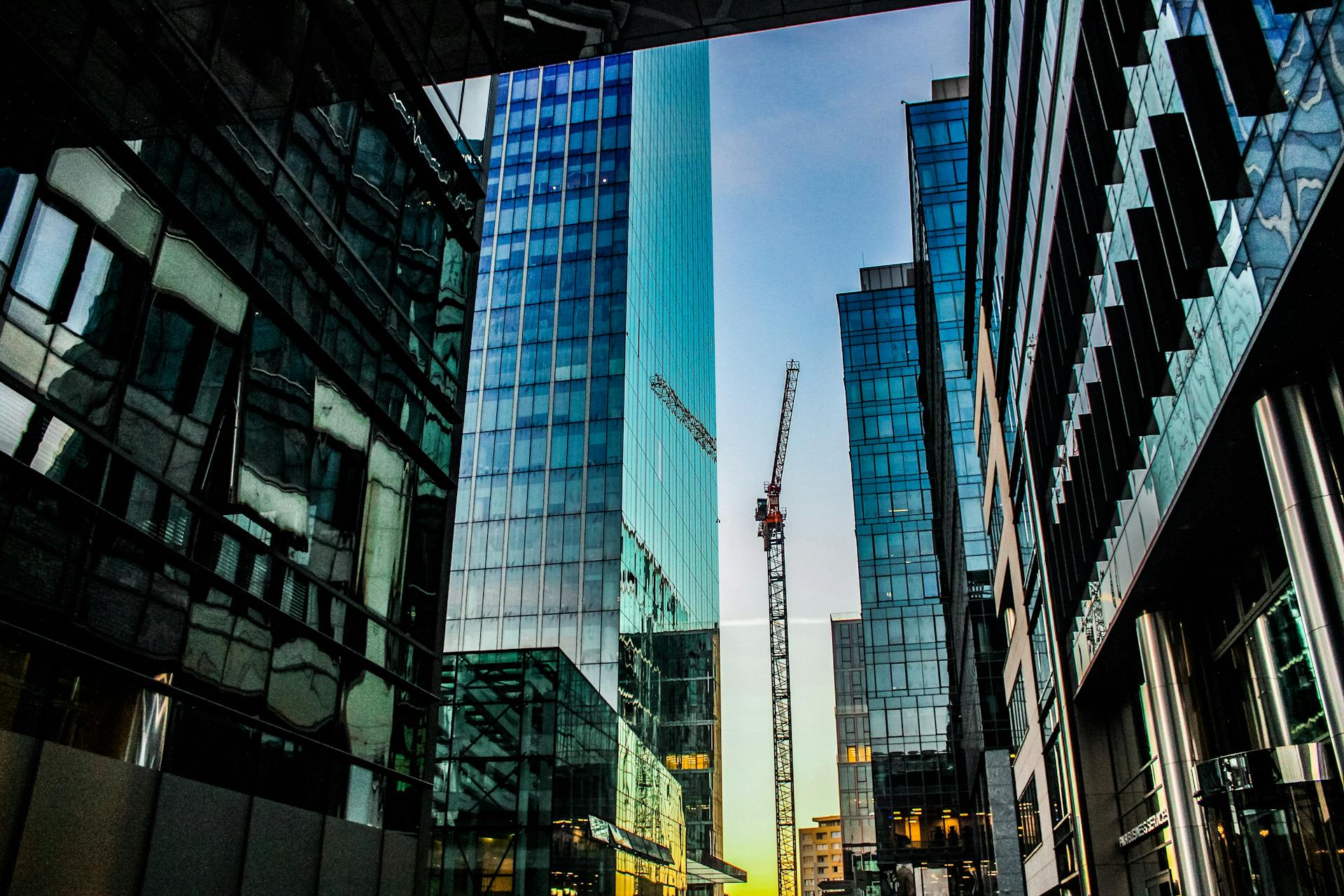 Vibrant cityscape of contemporary skyscrapers with glass reflections and construction crane.