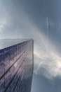 从低角度仰望摩天大楼，多云天空中有喷射轨迹反射着阳光