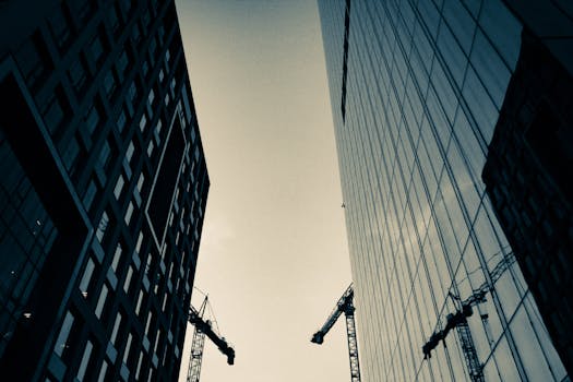 现代摩天大楼和起重机的剪影映衬在城市建设的背景中