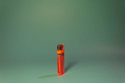 Orange Disposable Lighter on Green Surface