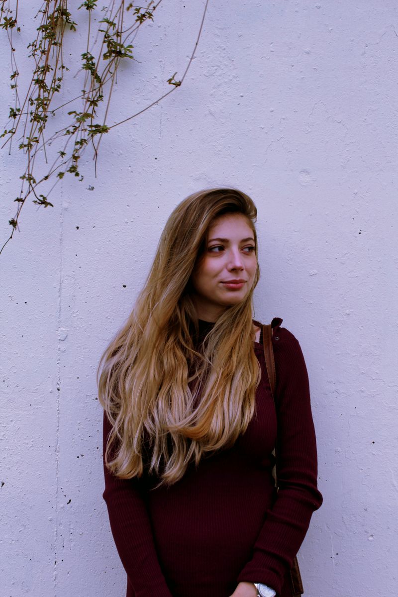 Woman with long light-brown hair against a lilac wall