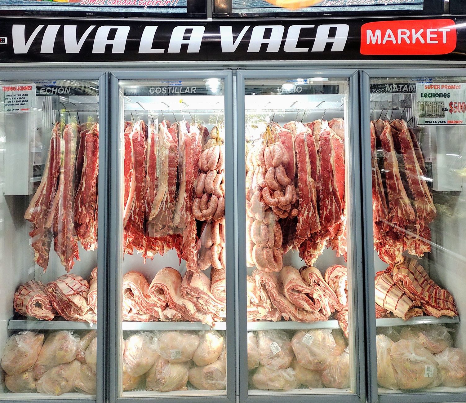 Fresh cuts of meat and sausages in a well-lit market refrigerator display