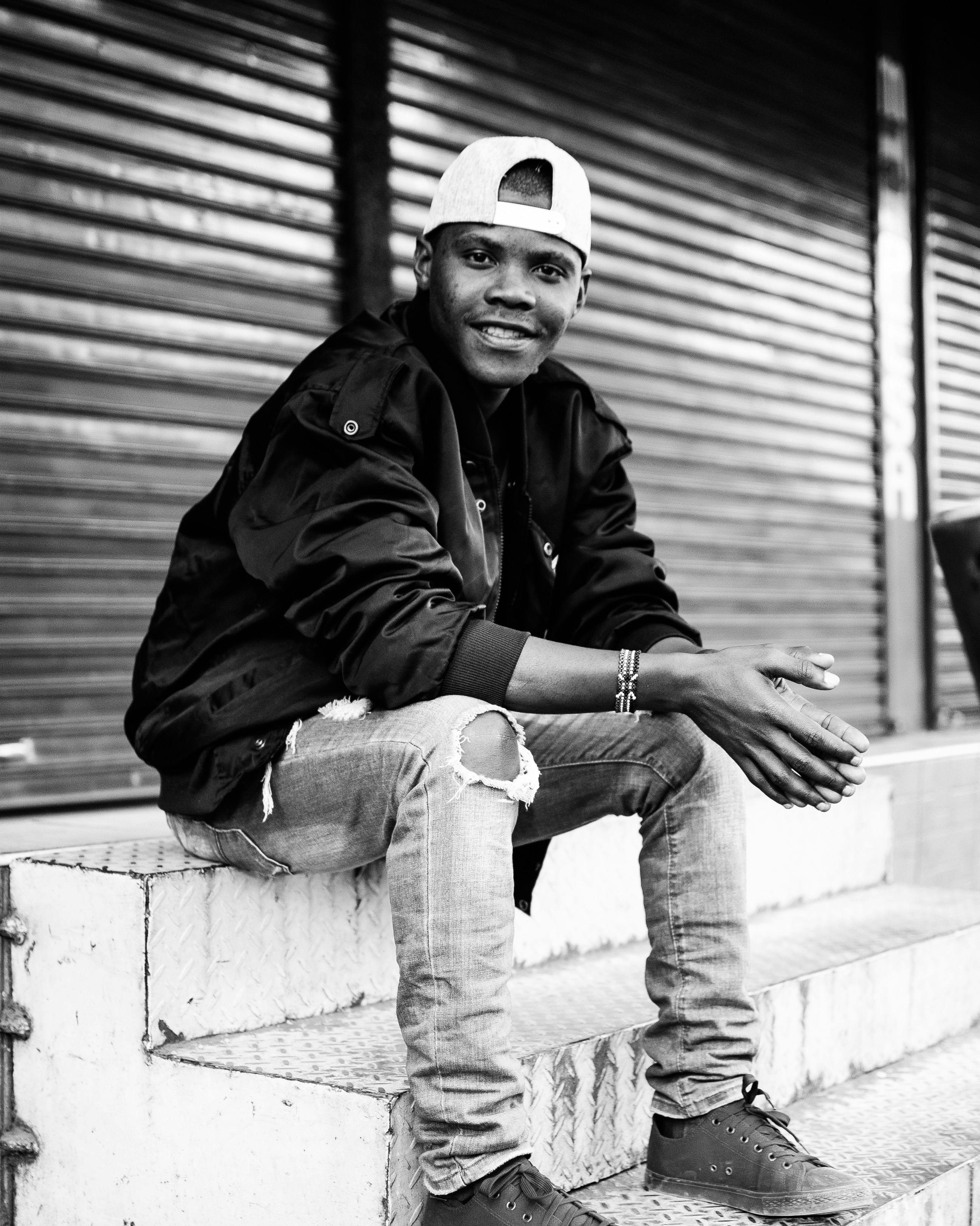 一位时尚年轻人穿着休闲装，自信地坐在城市背景下