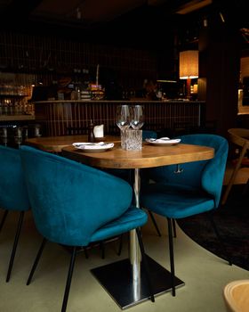Elegant restaurant table setup with teal chairs in a warmly lit Helsinki venue.