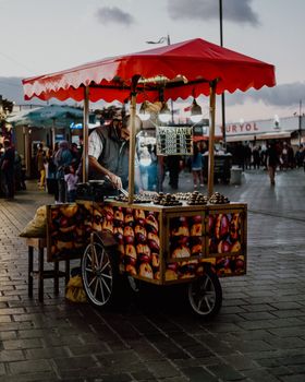 A street vendor selling roasted chestnuts in a bustling urban area at dusk.