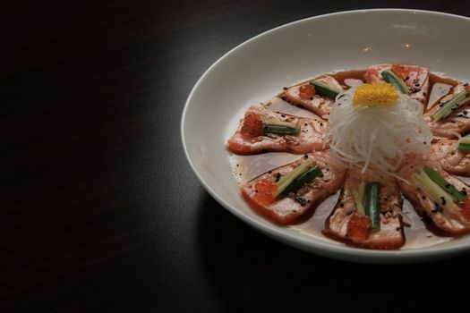 A tantalizing plate of salmon sashimi garnished with cucumber, radish, and roe served elegantly.