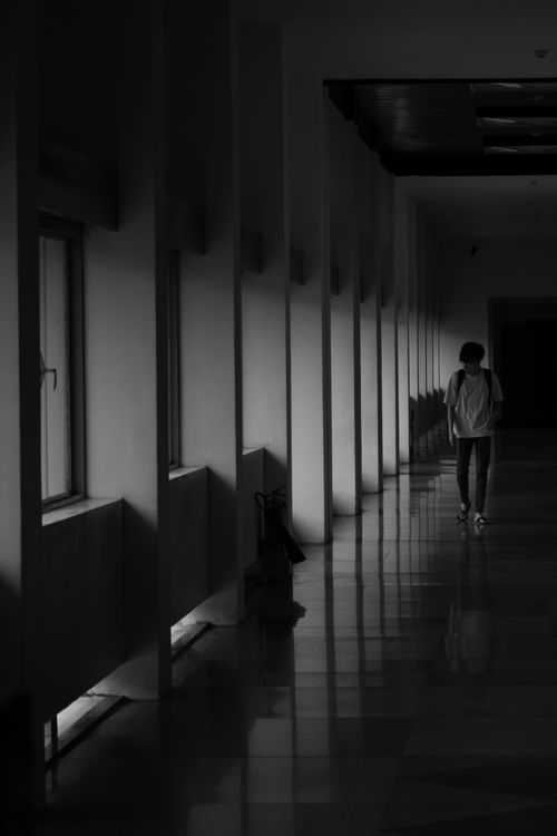 Free A solitary figure walks in a dimly lit hallway, creating a dramatic black and white scene in Vietnam. Stock Photo