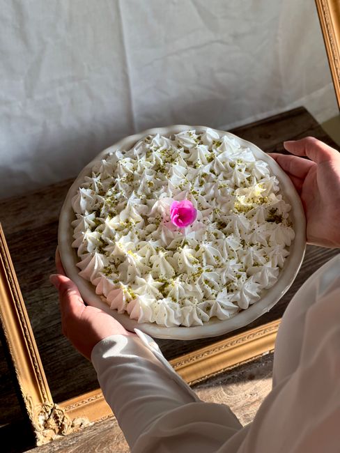 A glass bowl of glossy, stiff-peaked whipped cream with a piping bag and star tip resting beside it, ready to decorate a cake.