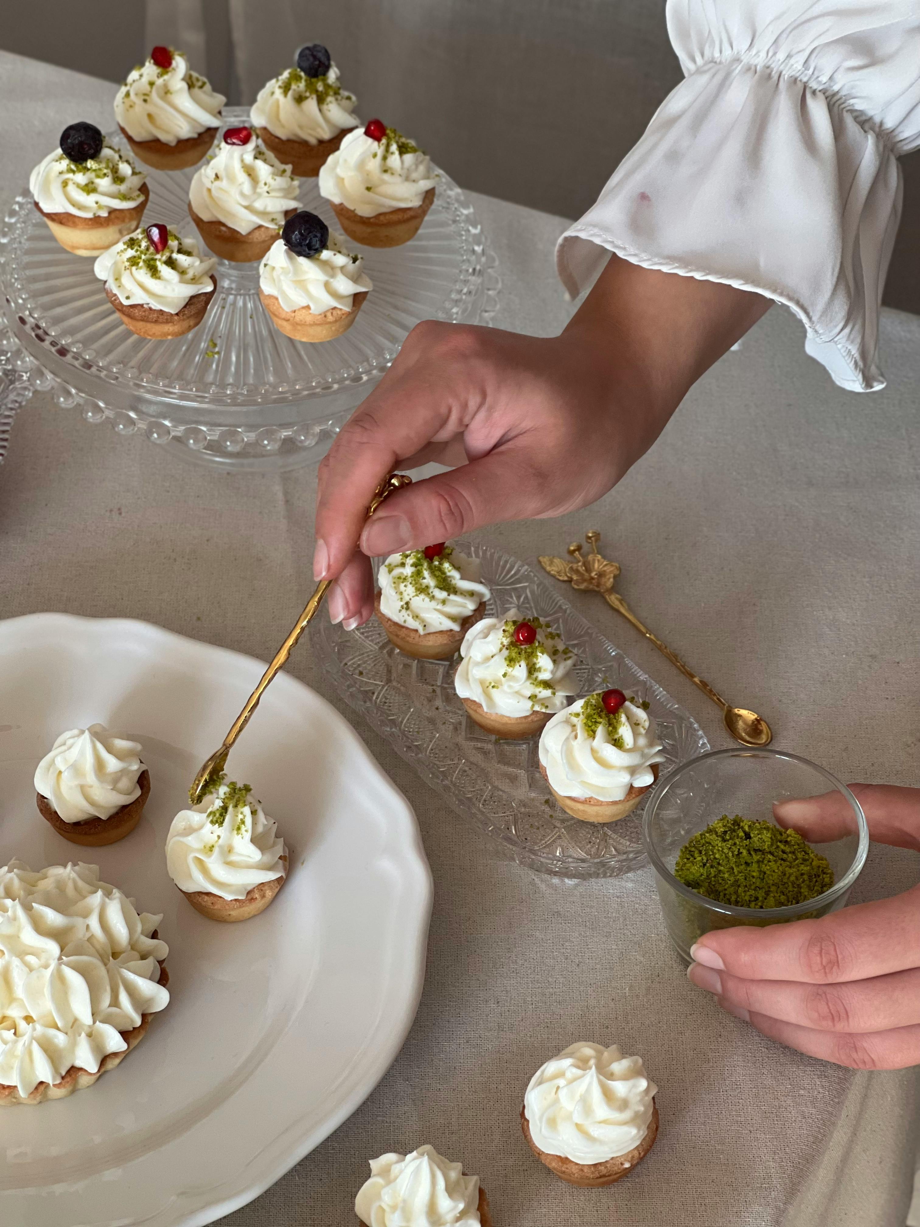Elegant decoration of cupcakes with cream and green garnish, showcasing homemade dessert artistry.