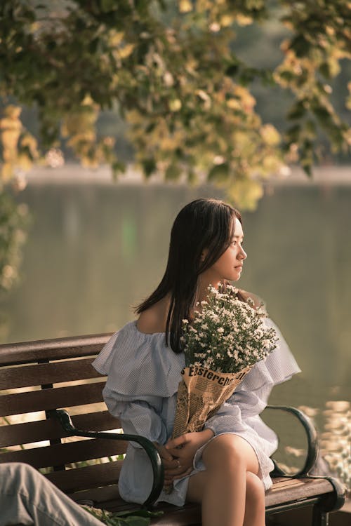 A Woman in Off Shoulder Dress Sitting on the Bench