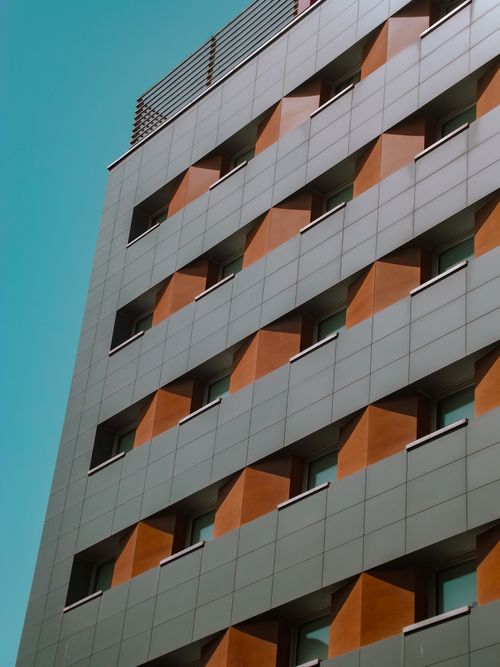 Free Close-up view of a modern building facade displaying a geometric pattern against a clear sky. Stock Photo