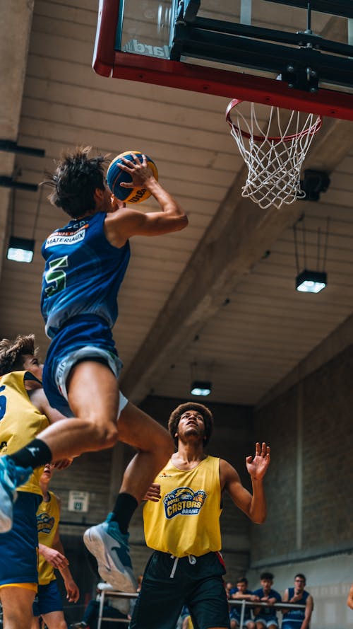 Photo of a Basketball Player Jumping to a Backboard