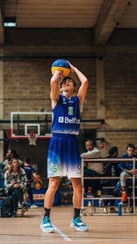 Young basketball player taking a shot indoors at a Belgian court.