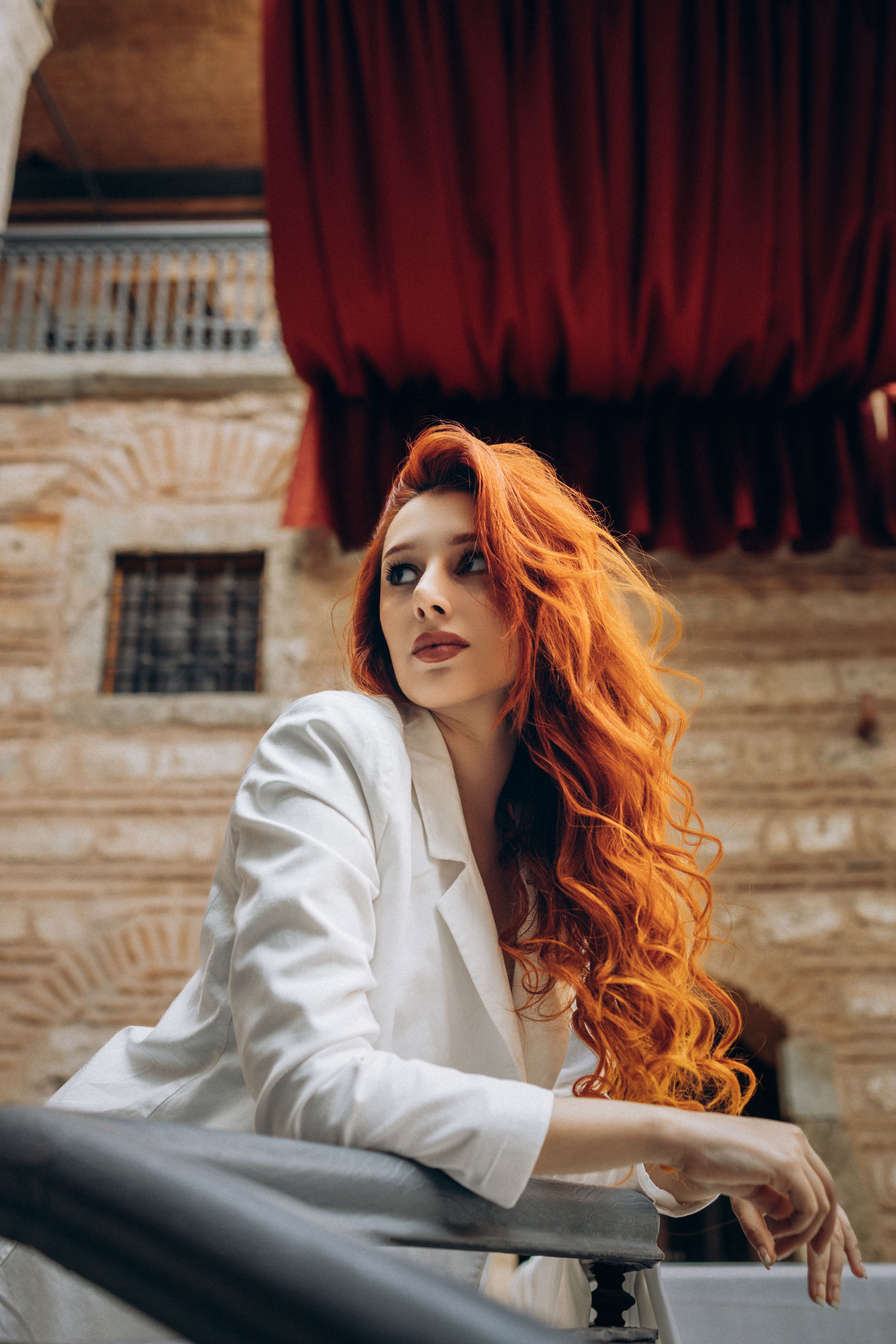 Elegant woman with red hair posing in a historical Turkish location.