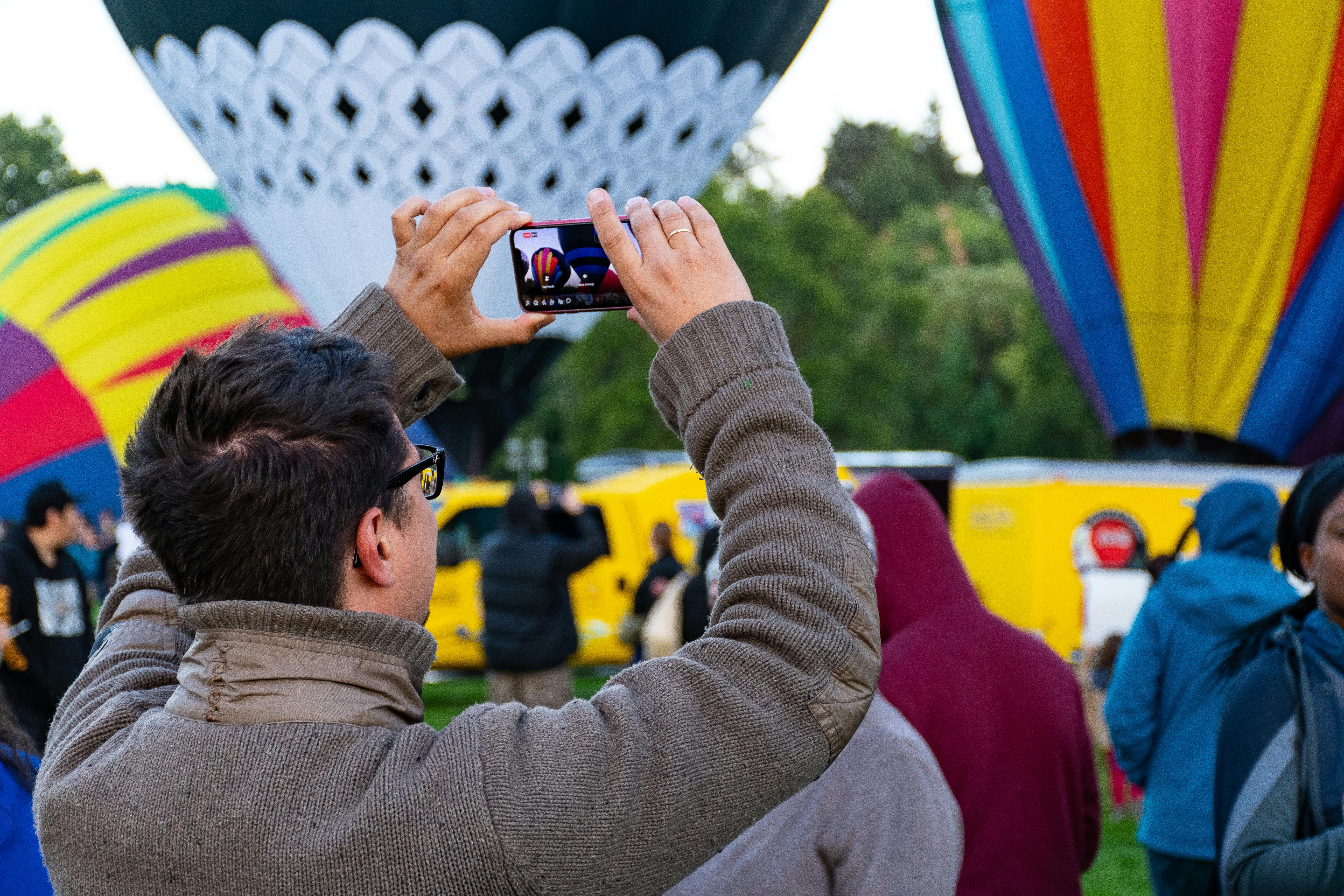 在户外节日上，一名男子拍摄了色彩缤纷的热气球，捕捉到了热闹的气氛
