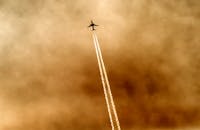 一架飞机引人注目的轮廓在戏剧性的金色天空中划出一道痕迹