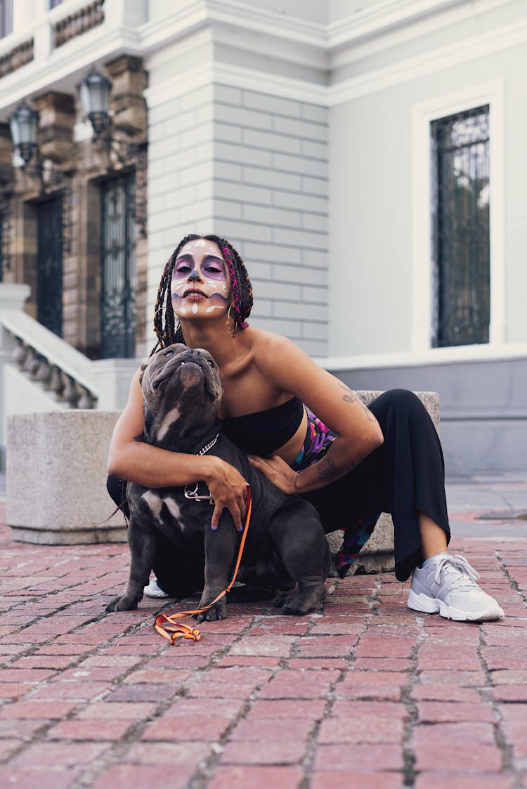 Woman With Face Painted Posing With Dog On Sidewalk