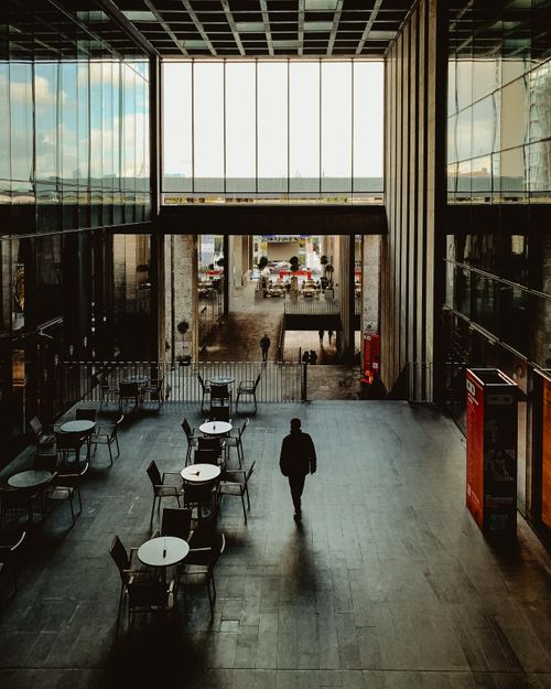 Free Silhouetted person walking inside a spacious modern cafe during the day. Stock Photo