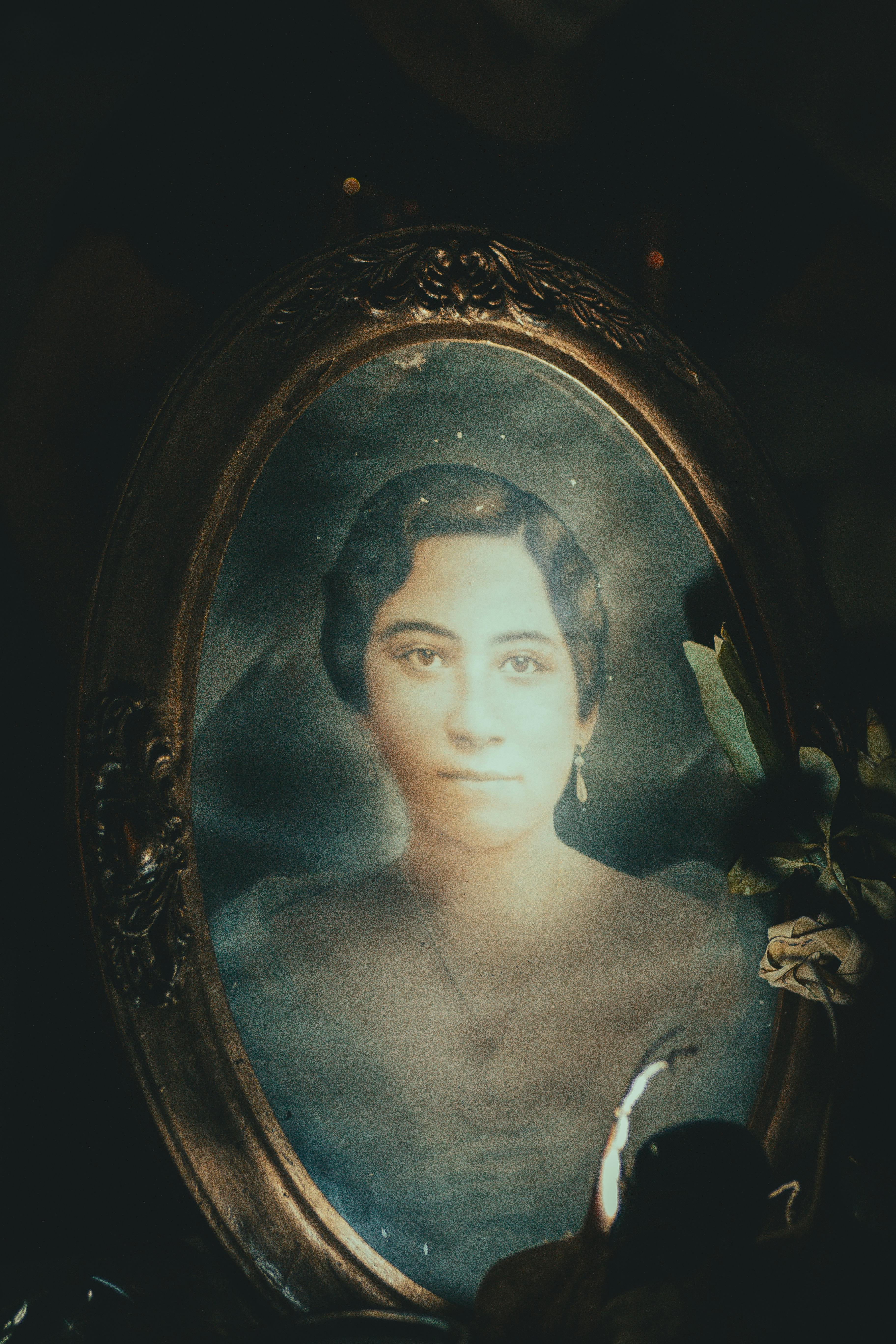 An antique framed portrait of a woman with a serene aura and vintage style.