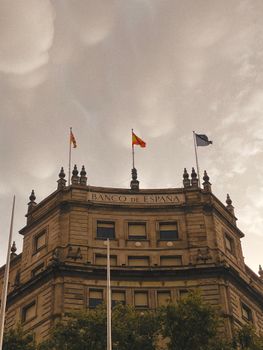 Captivating view of the Banco de España building in Madrid with a dramatic cloudy sky backdrop.