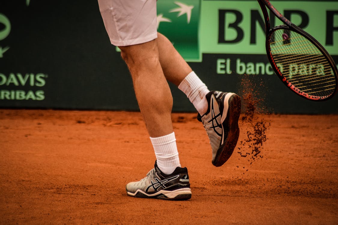 Man Wearing Black-and-white Asics Athletic Shoes Holding Racket