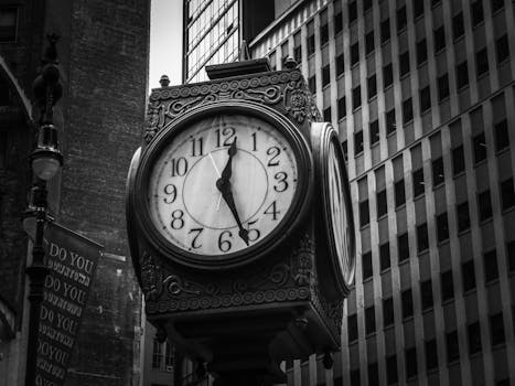 Black and white photo of a vintage clock against skyscrapers in New York City.