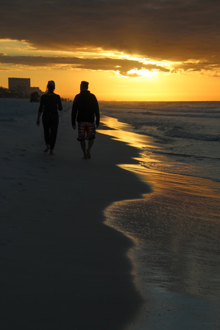 Silhouette Of A Couple Walking On The Beach During Sunset