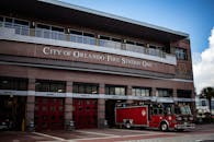 奥兰多市一号消防站外停着一辆红色消防车，天空晴朗，建筑现代