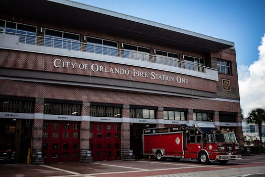 奥兰多市一号消防站外停着一辆红色消防车，天空晴朗，建筑现代