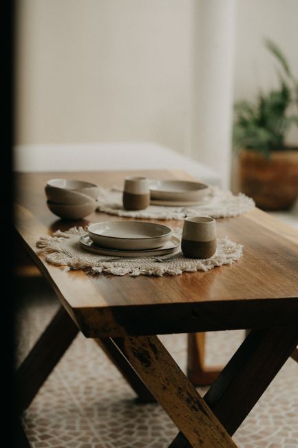 A beautifully set table with ceramic plates and mugs in earthy tones, indoors.
