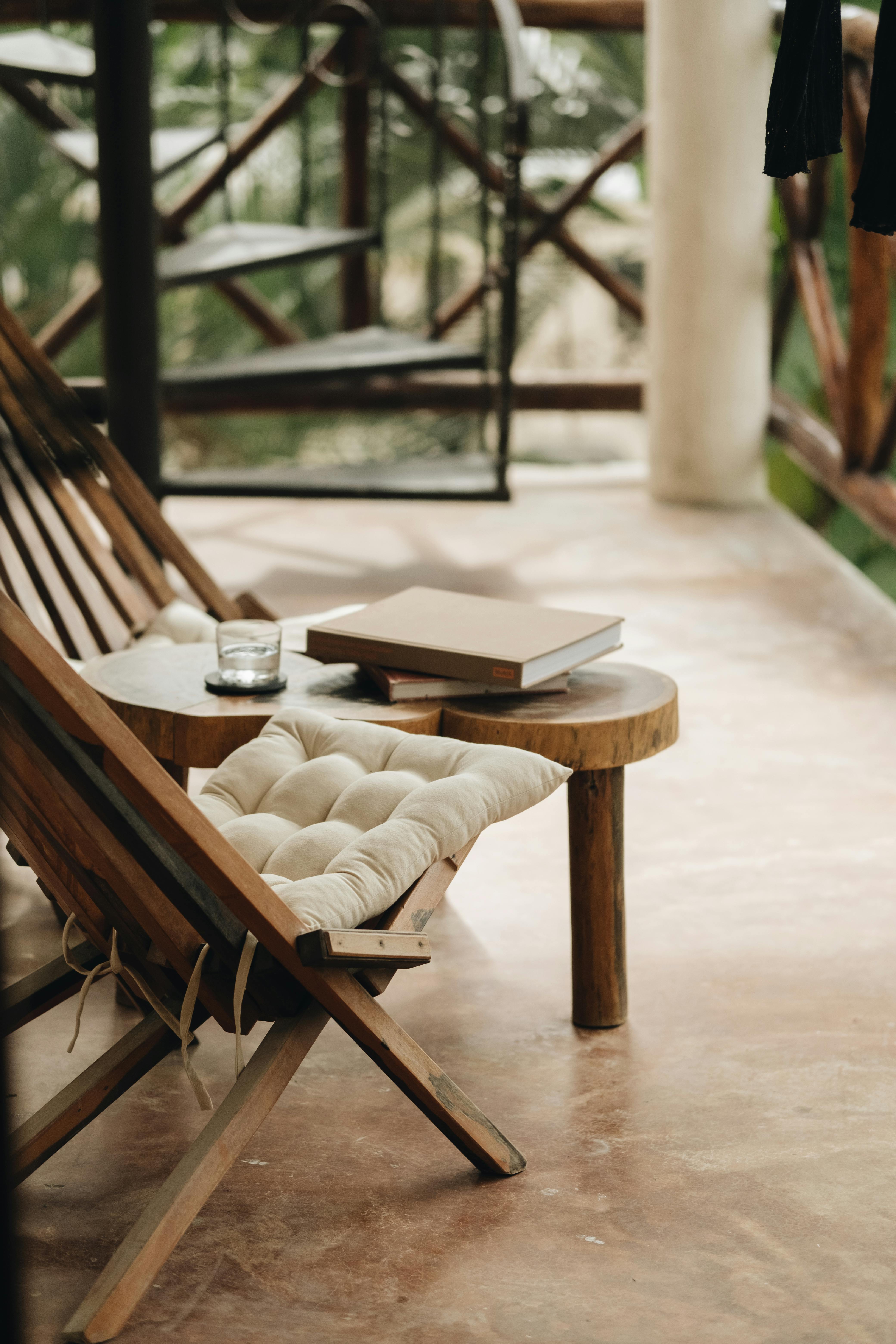 Relaxing patio with wooden chairs, table, and a drinking glass on a sunny day.