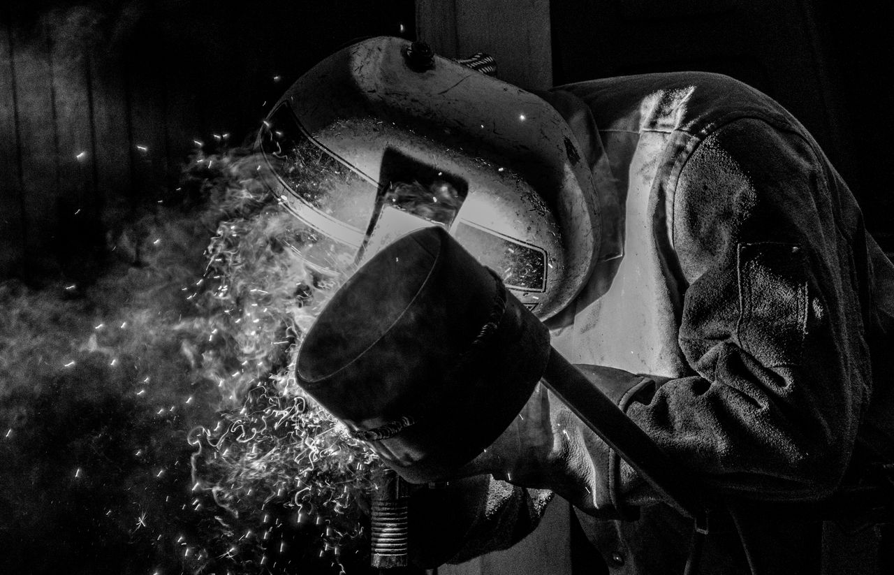 Black and white photograph of a welder at work, sparks flying — photo by Irbin Medina on Pexels