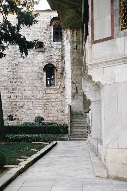 Free Peaceful stone courtyard featuring historical architecture, stairs, and landscaping. Stock Photo
